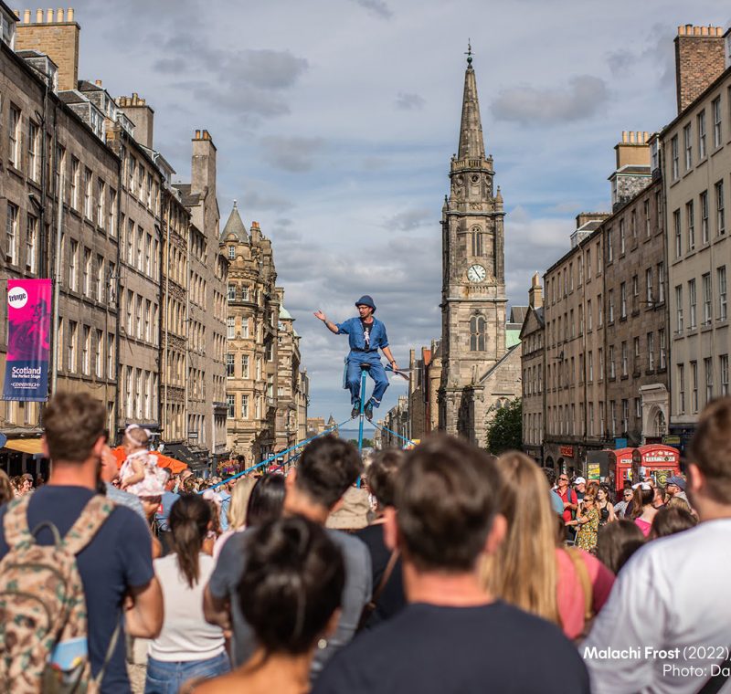 large crowds watching a performer in the high street at Edinburgh Fringe Festival